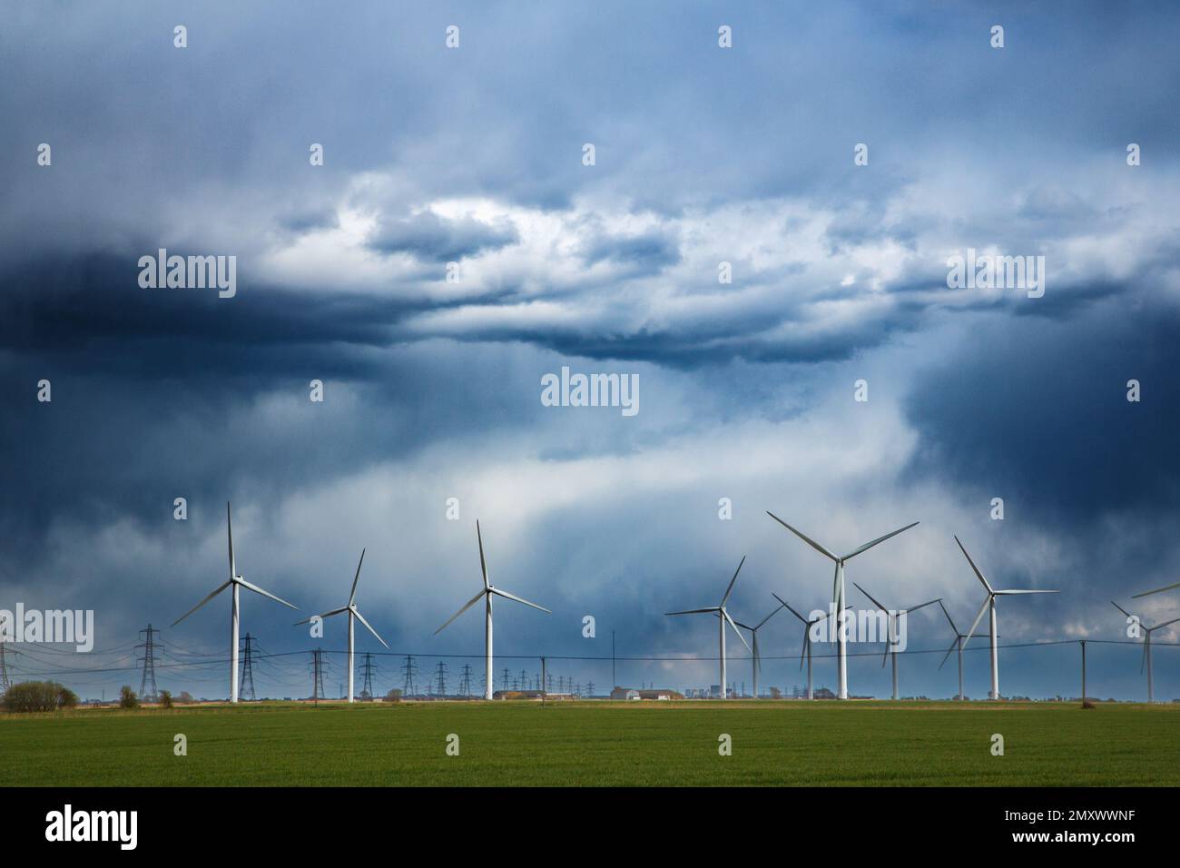Turbine eoliche e piloni elettrici, cielo drammatico, fattoria eoliche onshore Little cheyne, palude romney, kent, regno unito Foto Stock