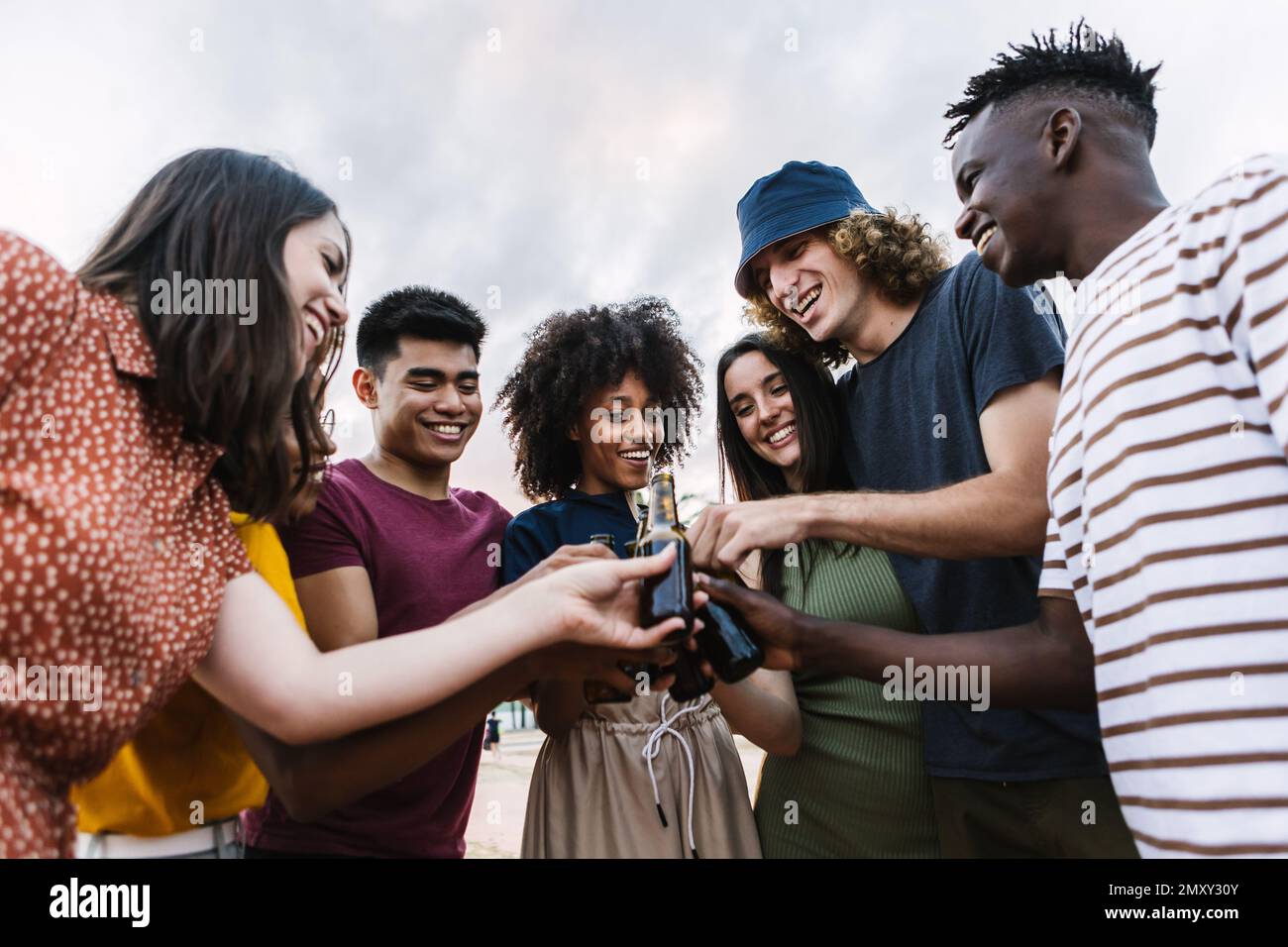 Giovane gruppo di amici multietnici che festeggiano insieme allietando con la birra Foto Stock