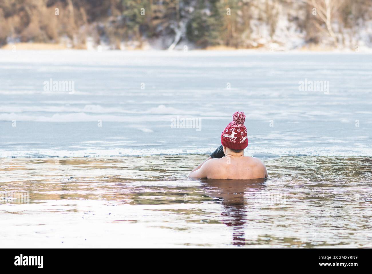 Bel ragazzo o uomo che fa il bagno di ghiaccio nelle acque fredde di un lago. Metodo WIM Hof, terapia fredda, tecniche di respirazione, yoga e meditazione Foto Stock
