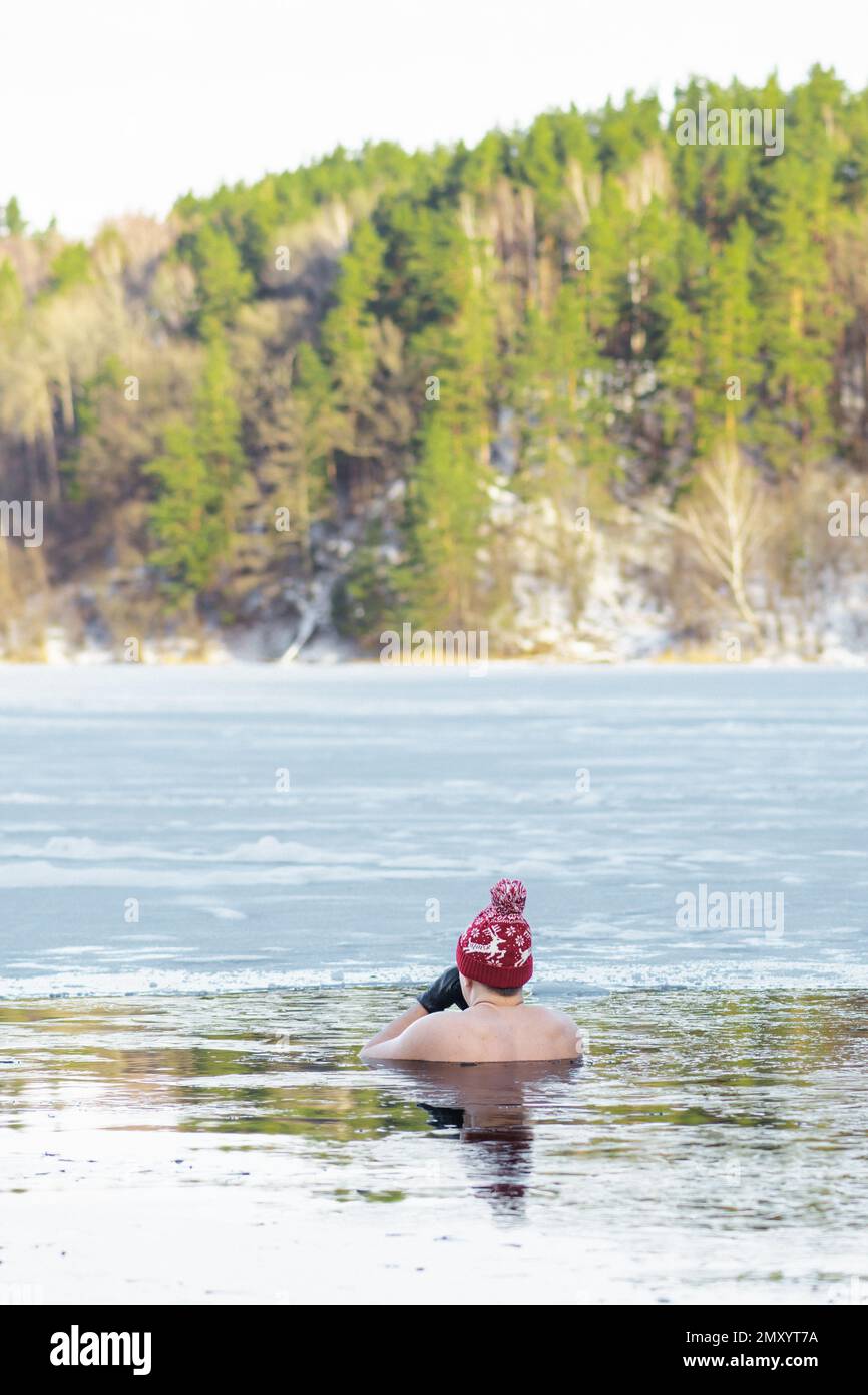 Bel ragazzo o uomo che fa il bagno di ghiaccio nelle acque fredde di un lago. Metodo WIM Hof, terapia fredda, tecniche di respirazione, yoga e meditazione, verticale Foto Stock