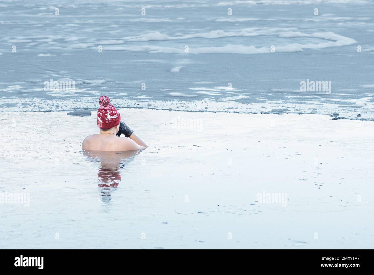 Bel ragazzo o uomo che fa il bagno di ghiaccio nelle acque fredde di un lago. Metodo WIM Hof, terapia fredda, tecniche di respirazione, yoga e meditazione Foto Stock