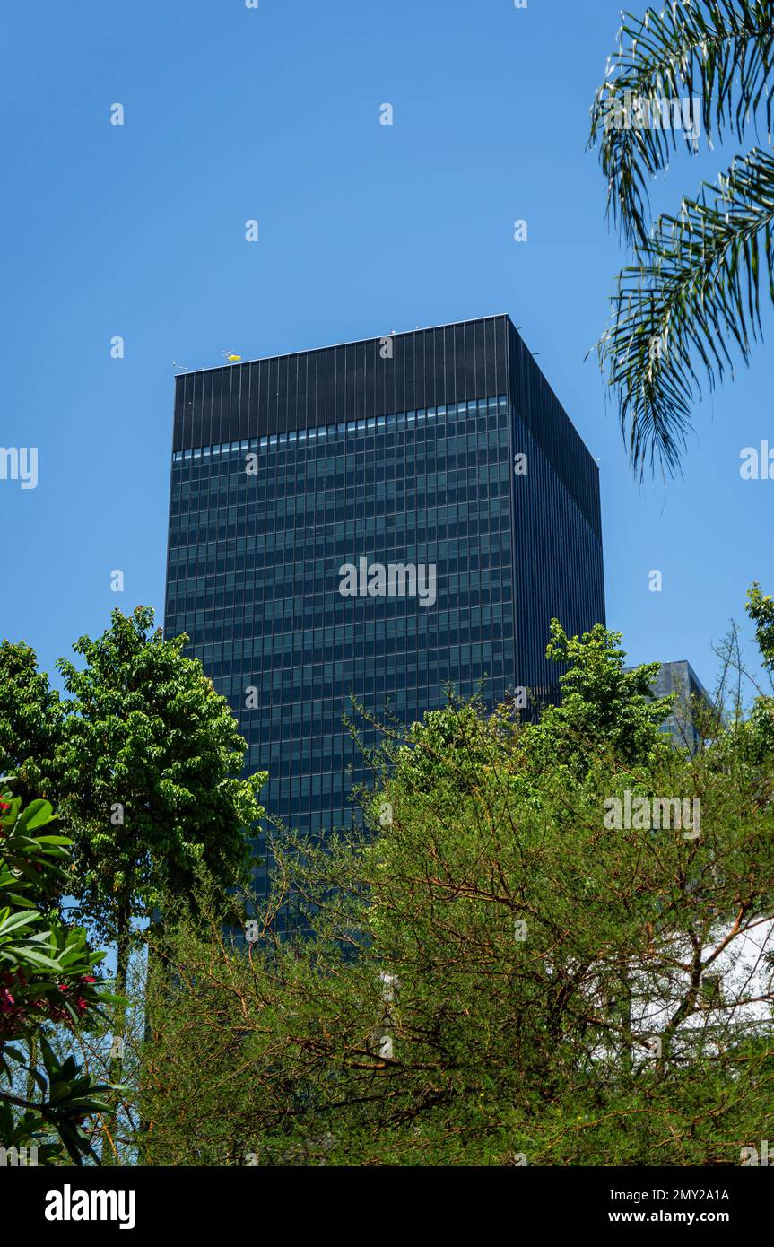 Vista dalla piazza Largo da Carioca del quartier generale BNDES torre dietro alcuni alberi situato nel quartiere Centro sotto estate mattina cielo chiaro. Foto Stock