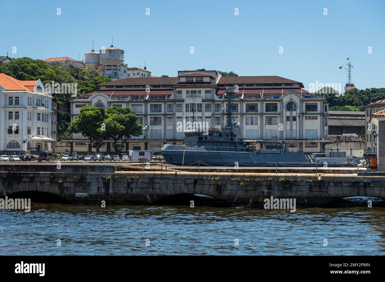 Vista in lontananza dell'edificio Naval Systems Analysis situato nell'isola di Ilha das Cobras, nelle acque della baia di Guanabara sotto il sole pomeriggio cielo azzurro Foto Stock