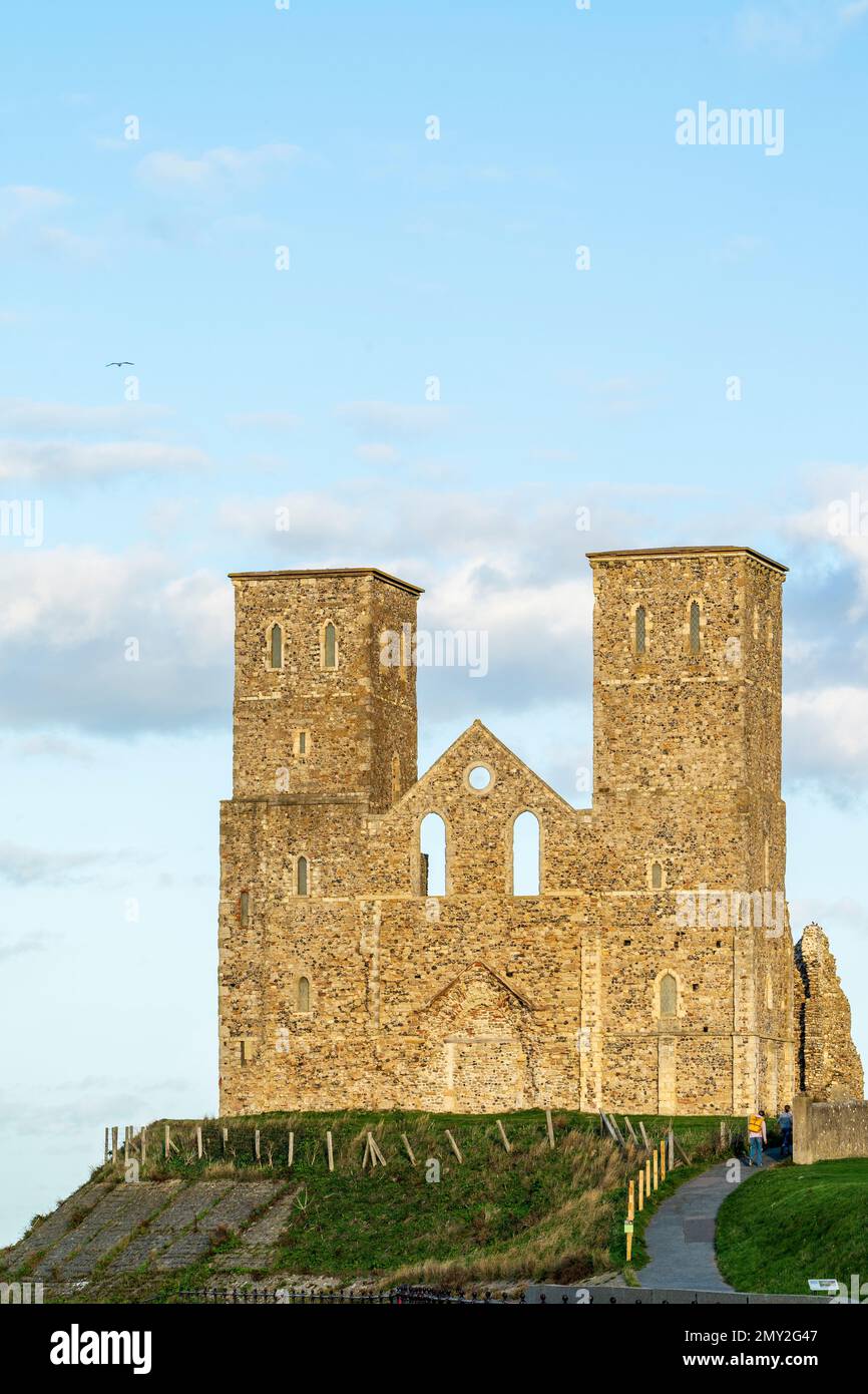 Le torri gemelle del 12th ° secolo delle rovine della chiesa di Reculver sul lungomare sulla costa del Kent al sole in autunno con cielo blu e nuvole. Foto Stock