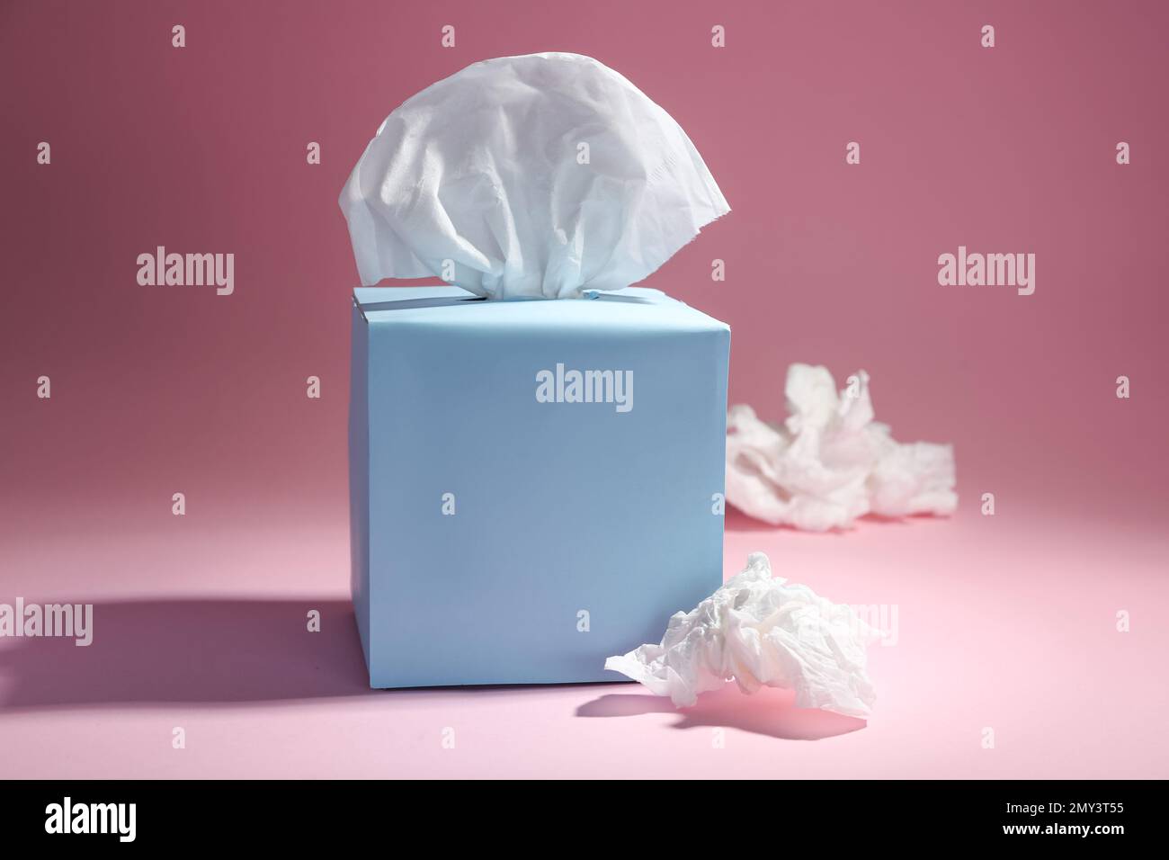 Scatola di carta fazzoletti e tovaglioli stropicciati usati su sfondo rosa Foto Stock