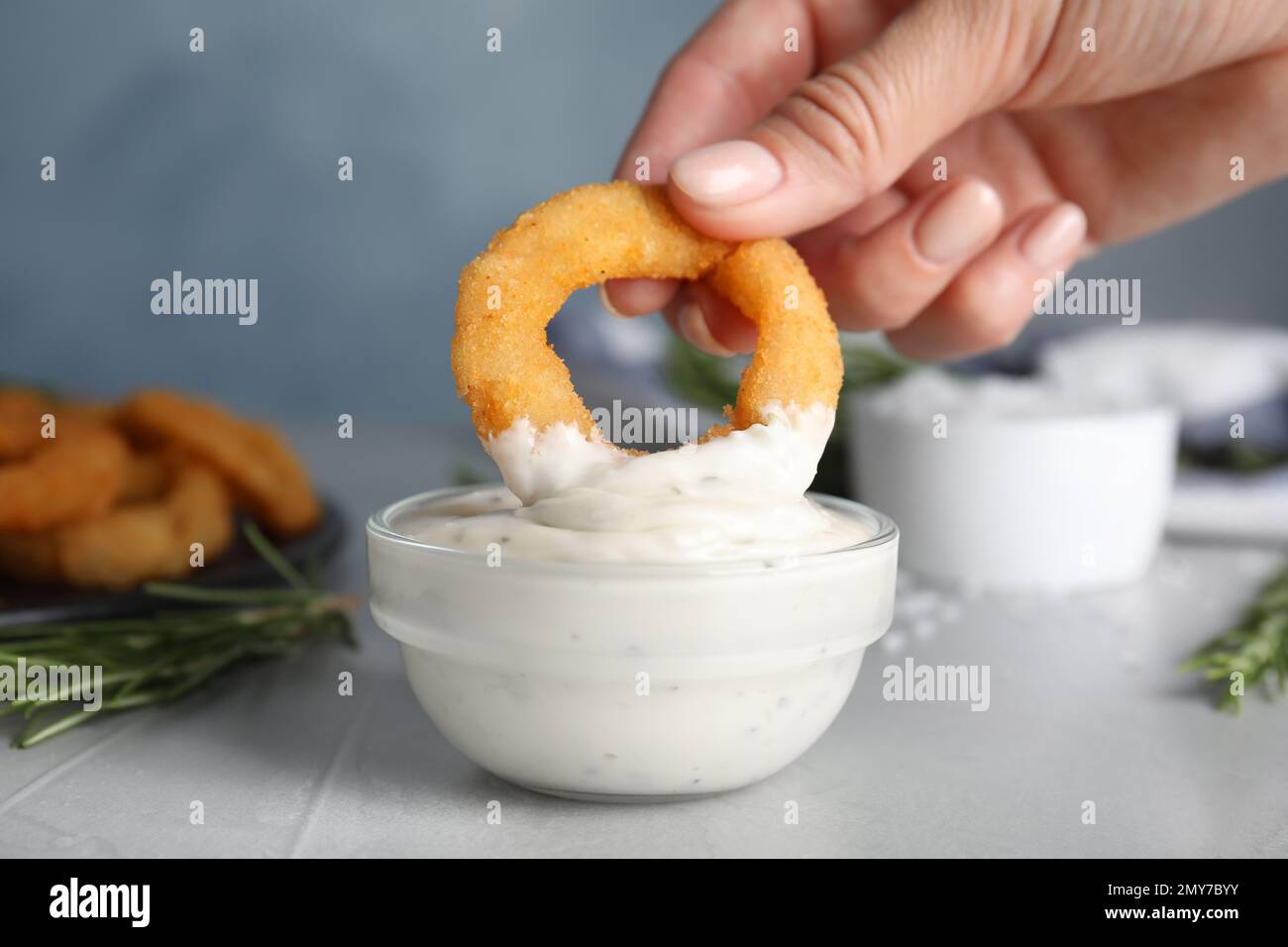 Donna che immerge croccante anello di cipolla fritta in salsa, primo piano  Foto stock - Alamy