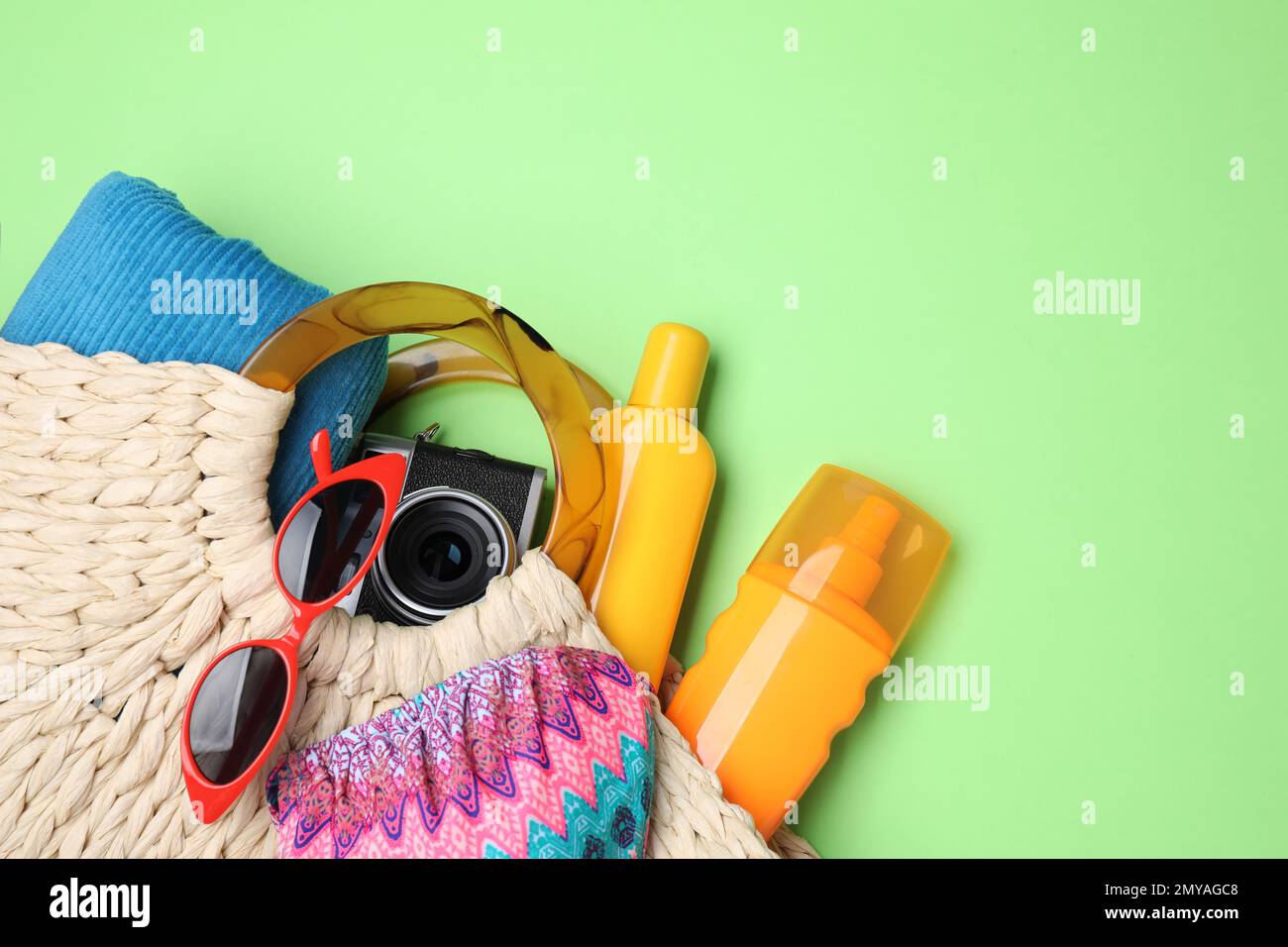 Borsa a maglia con oggetti da spiaggia su sfondo verde, piatto. Spazio per il testo Foto Stock