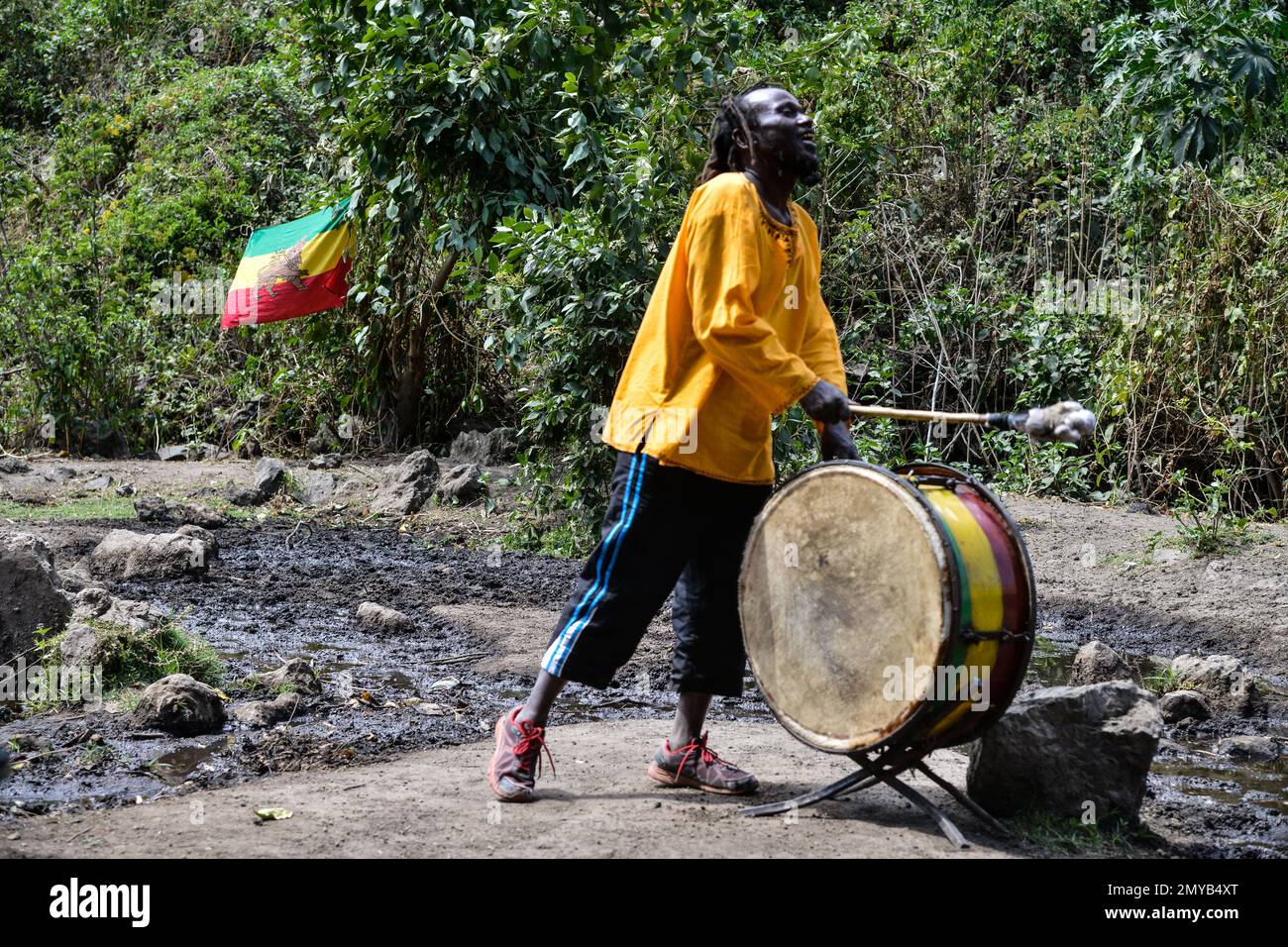 Un aderente della setta Rastafari suona un tamburo durante la speciale riunione di preghiera e di culto del gruppo nella foresta Menengai a Bahati, nei pressi della città di Nakuru. La comunità di Nakuru Rastafari ha denunciato la decisione del governo di introdurre colture modificate genetiche in Kenya, affermando che il paese è benedetto dalla disponibilità di terreni fertili. Chiedono al governo di affondare più fori di trivellazione per aumentare l'irrigazione invece di consentire sementi GM. Pochi mesi dopo che il presidente William Rito ha preso il controllo del governo, ha annunciato l'inversione di un divieto di 10 anni sulla coltivazione di GM per affrontare la sicurezza alimentare causata da contro Foto Stock