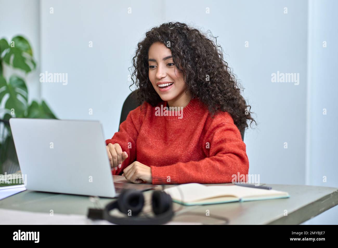 Felice sorpresa giovane donna di affari latina che guarda il portatile. Foto Stock