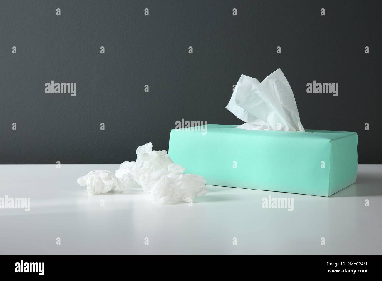 Fazzolettini di carta usati e scatola su tavolo bianco Foto Stock