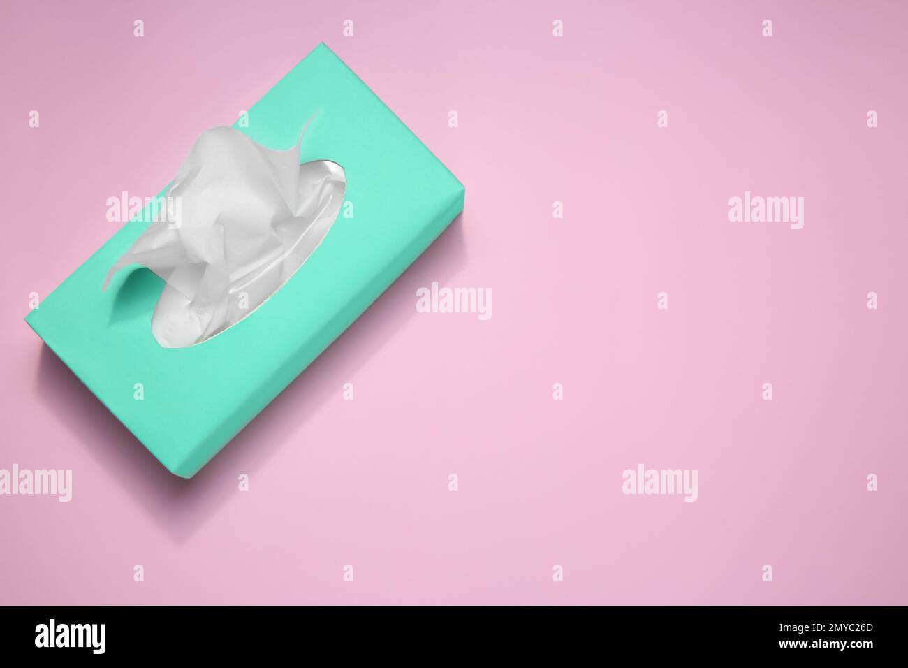 Scatola con fazzolettini di carta su sfondo rosa, vista dall'alto. Spazio per il testo Foto Stock