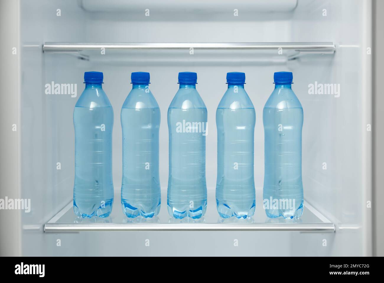 Molte bottiglie con acqua fresca sul ripiano del frigorifero Foto Stock