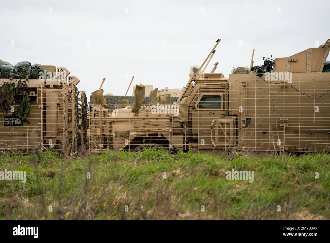 Primo piano di diversi veicoli di pattuglia protetti dall'esercito britannico Mastiff sotto una rete verde di mimetizzazione, Wiltshire UK Foto Stock