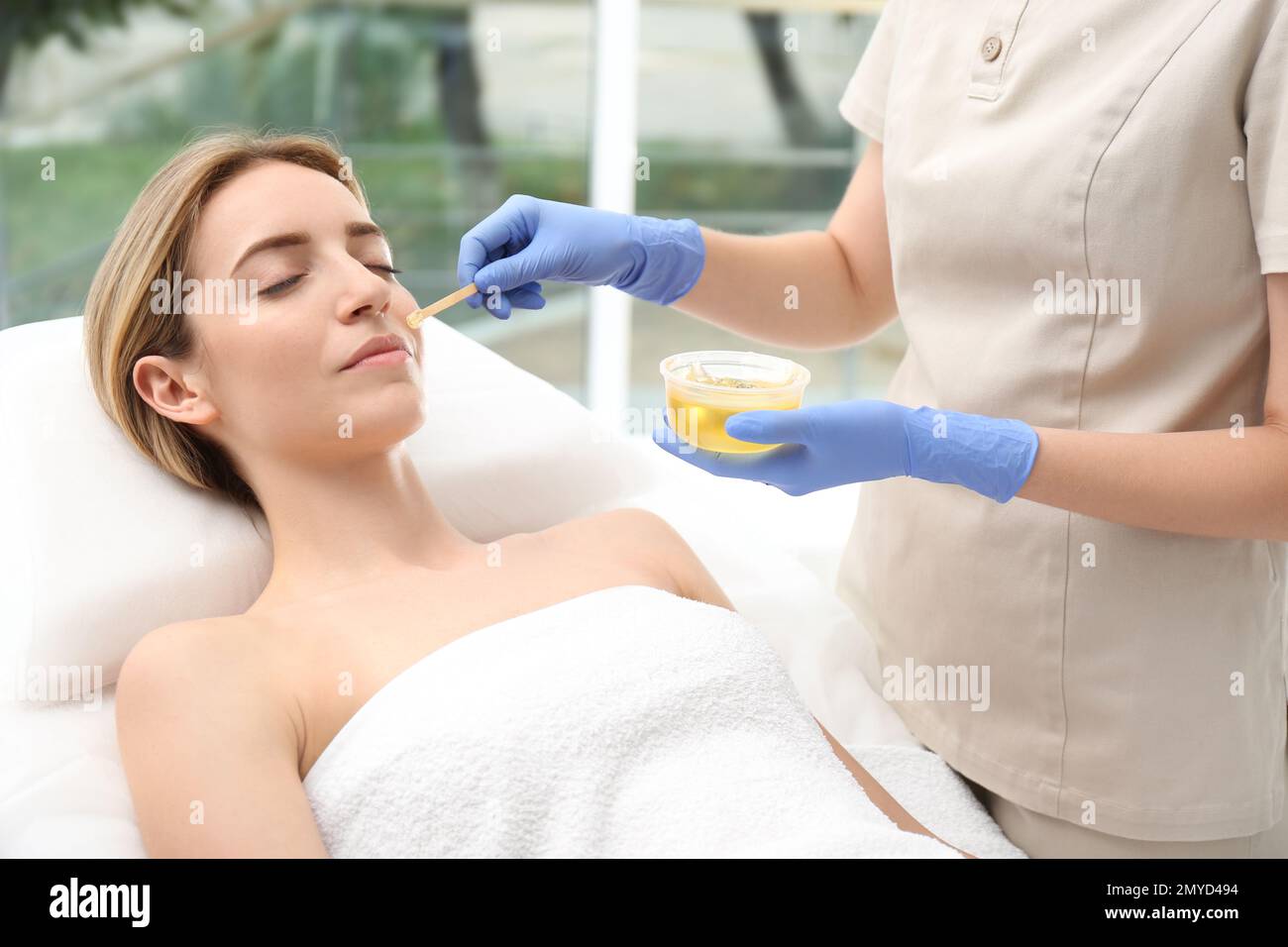 Bella donna che ottiene l'epilazione della cera del viso in salone Foto Stock