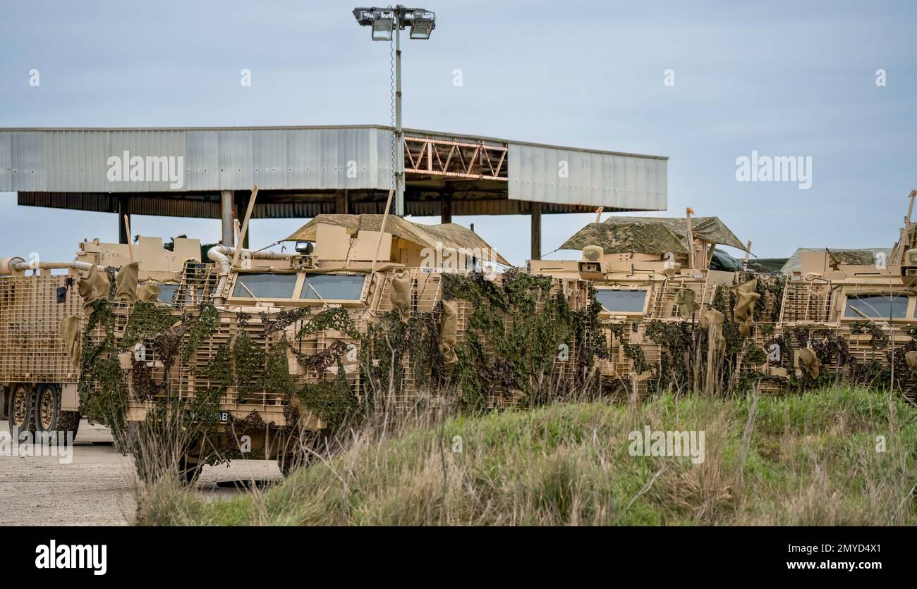 Primo piano di diversi veicoli di pattuglia protetti dall'esercito britannico Mastiff sotto una rete verde di mimetizzazione, Wiltshire UK Foto Stock