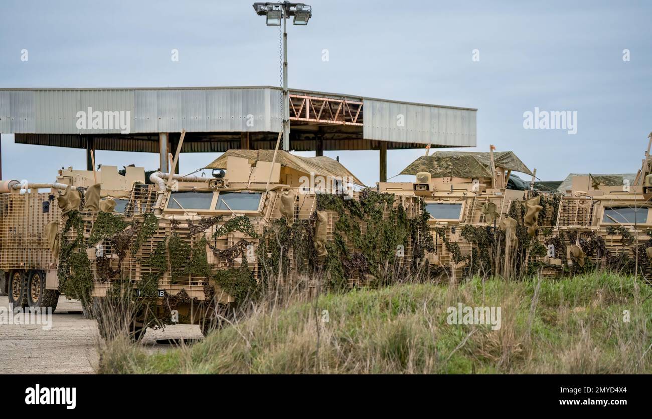 Primo piano di diversi veicoli di pattuglia protetti dall'esercito britannico Mastiff sotto una rete verde di mimetizzazione, Wiltshire UK Foto Stock
