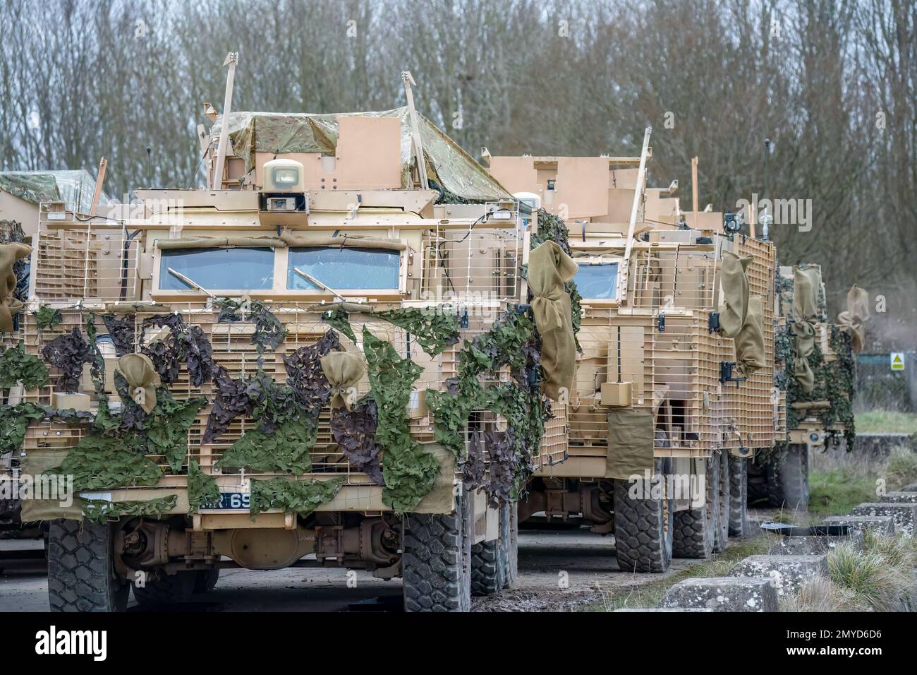 Primo piano di diversi veicoli di pattuglia protetti dall'esercito britannico Mastiff sotto una rete verde di mimetizzazione, Wiltshire UK Foto Stock