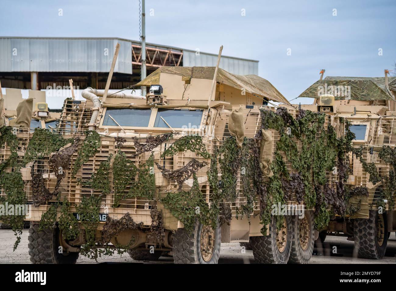 Primo piano di diversi veicoli di pattuglia protetti dall'esercito britannico Mastiff sotto una rete verde di mimetizzazione, Wiltshire UK Foto Stock