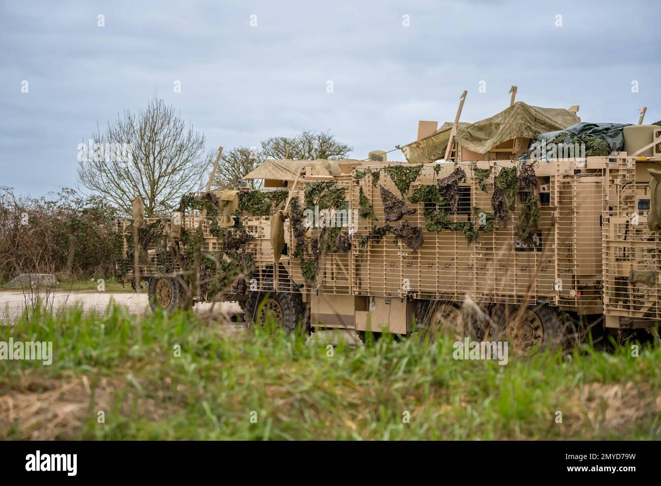 Primo piano di diversi veicoli di pattuglia protetti dall'esercito britannico Mastiff sotto una rete verde di mimetizzazione, Wiltshire UK Foto Stock