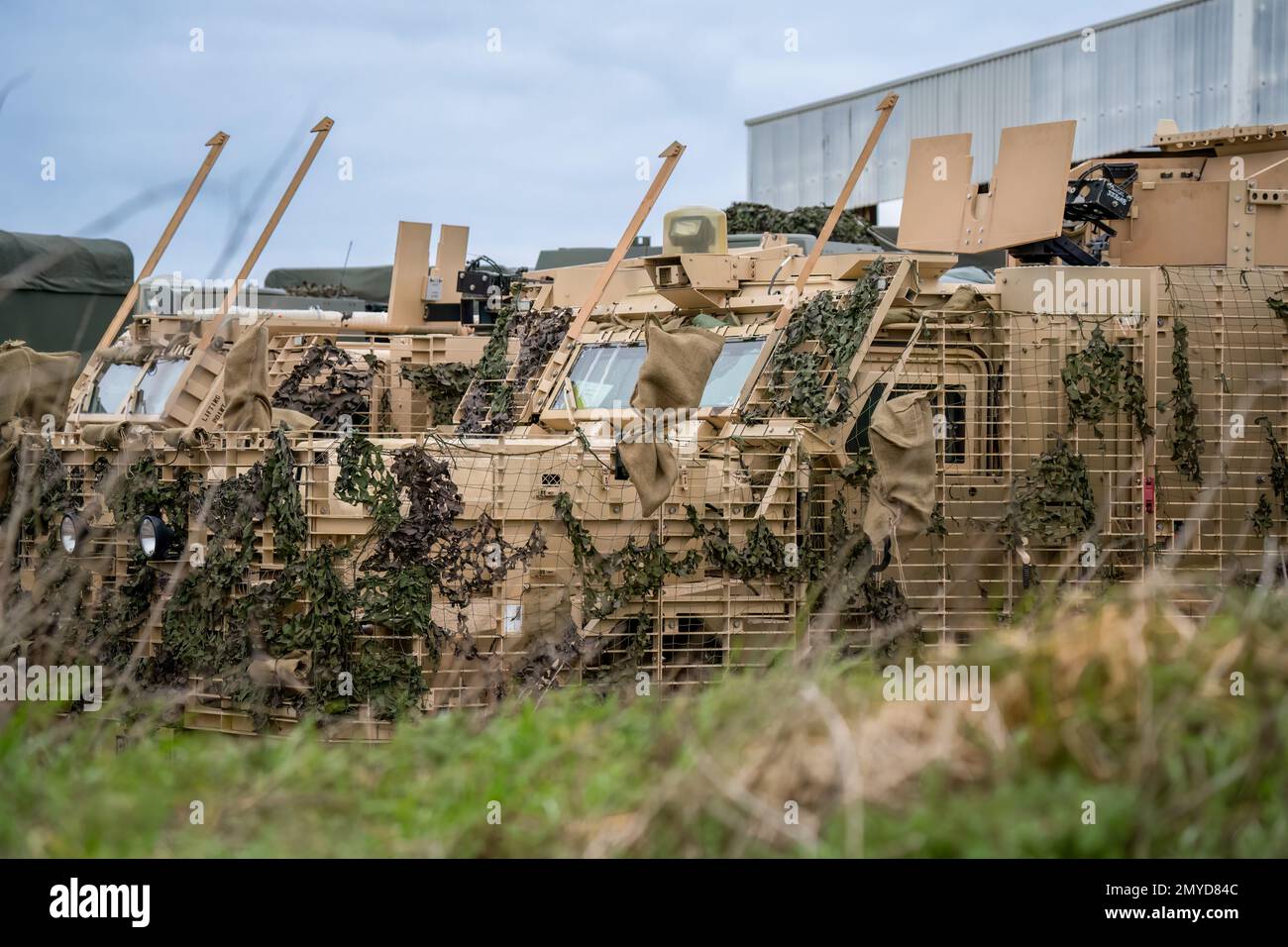 Primo piano di diversi veicoli di pattuglia protetti dall'esercito britannico Mastiff sotto una rete verde di mimetizzazione, Wiltshire UK Foto Stock