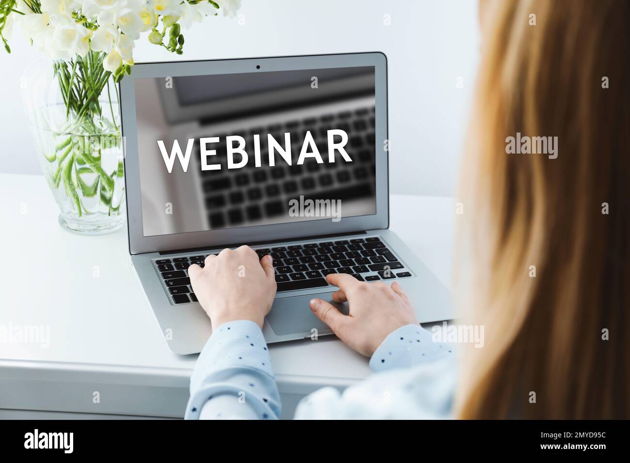 Donna che lavora su un notebook moderno al tavolo bianco al chiuso, primo piano. Webinar aziendale Foto Stock