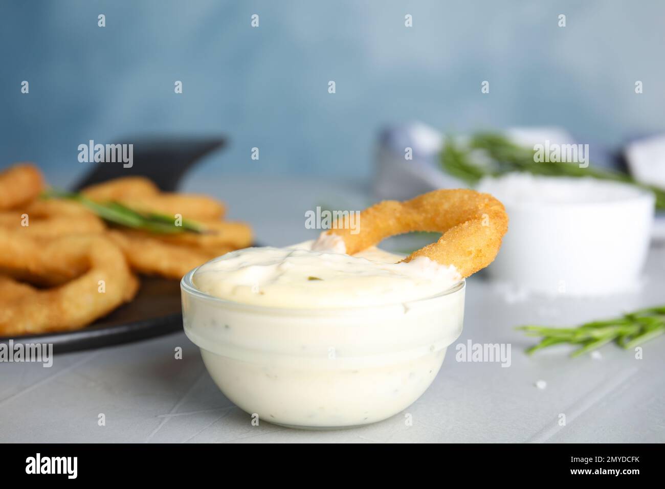 Anello di cipolla fritto con salsa sul tavolo grigio Foto Stock