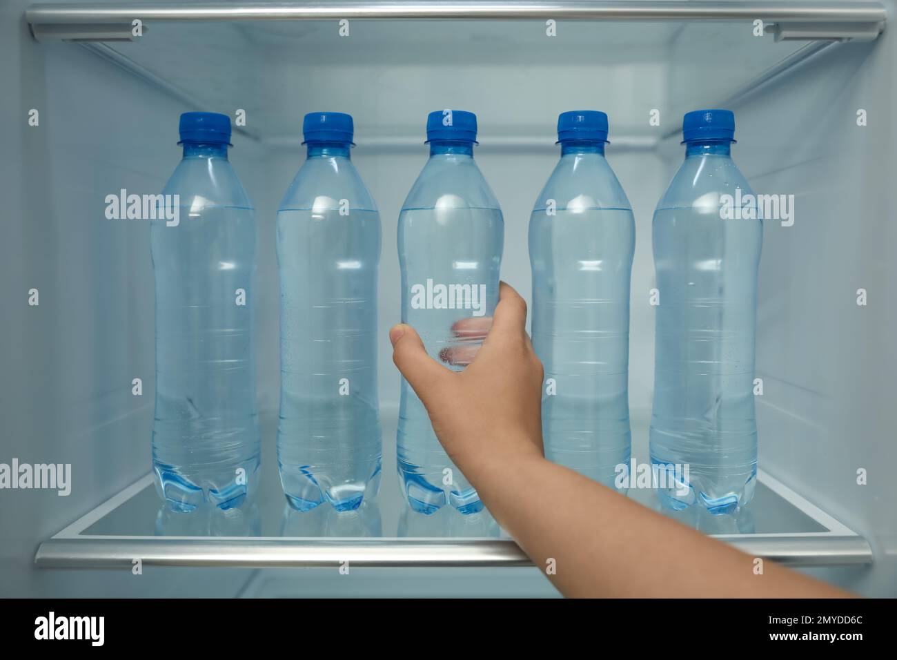 Donna che prende una bottiglia di acqua fresca dalla mensola del frigorifero, primo piano Foto Stock
