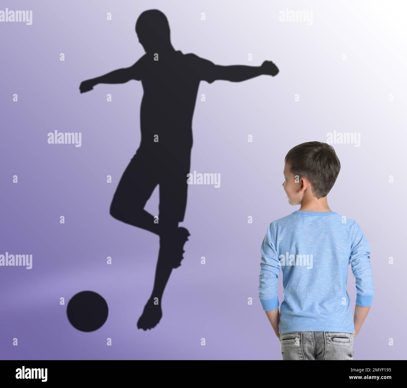 Ragazzino che sogna di essere un giocatore di calcio. Silhouette dell'uomo dietro il bambino Foto Stock