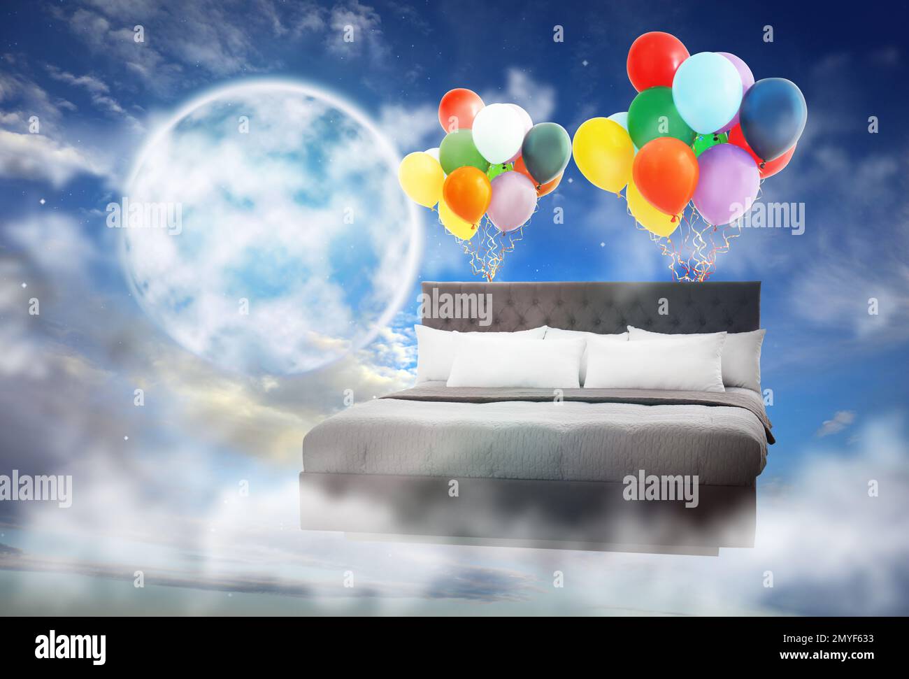 Sogni dolci. Letto con aerostati luminosi vicino alla luna piena in cielo nuvoloso Foto Stock
