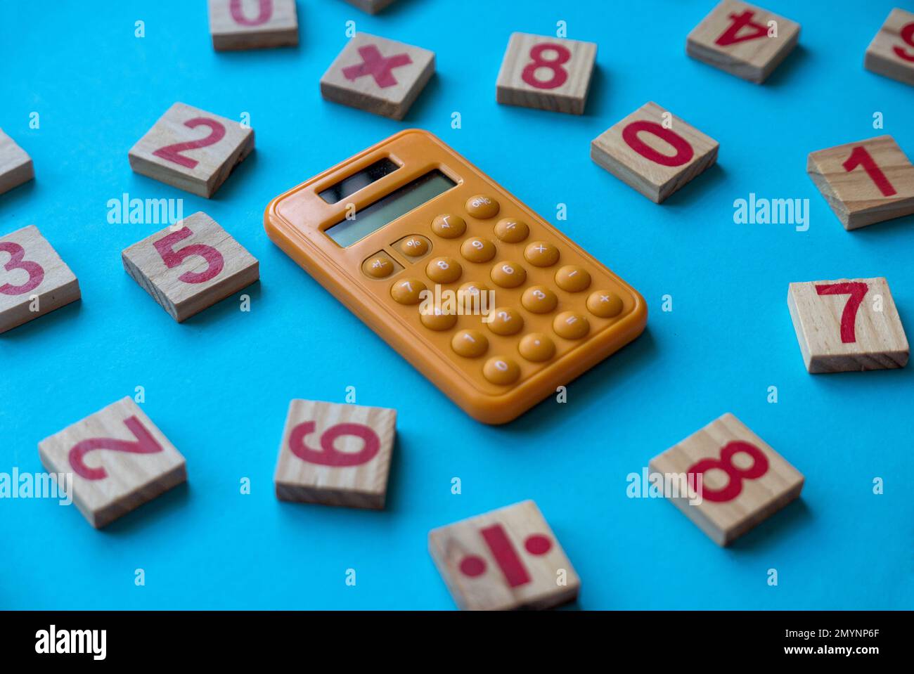 Calcolatrice e un numero di legno e simbolo matematico su sfondo blu. Foto Stock