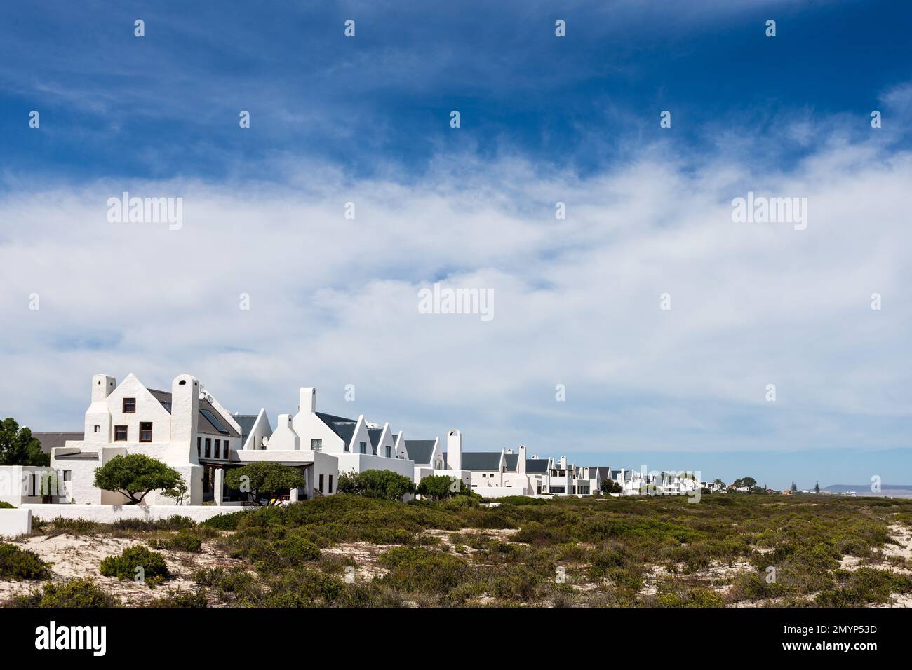 Fila di case bianche in uno stile mediterraneo di architettura in una cittadina costiera rurale sul mare nella parte occidentale del Capo, Sud Africa Foto Stock