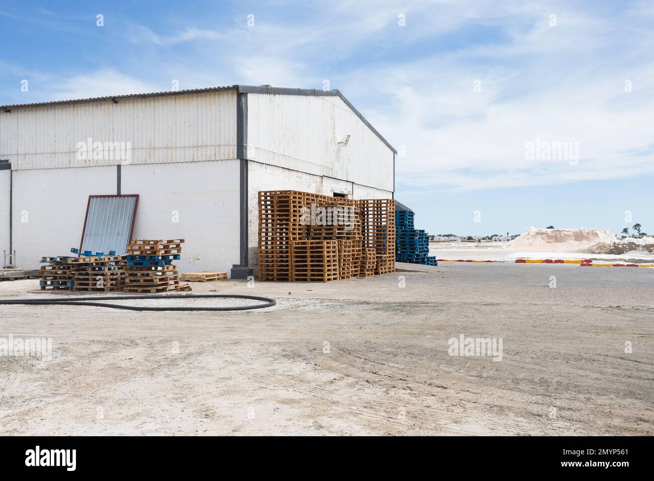 Pallet e casse di legno impilati all'esterno di un capannone o di un edificio in una fabbrica di sale nel Capo Occidentale, Sud Africa Concept Industry e scena industriale Foto Stock