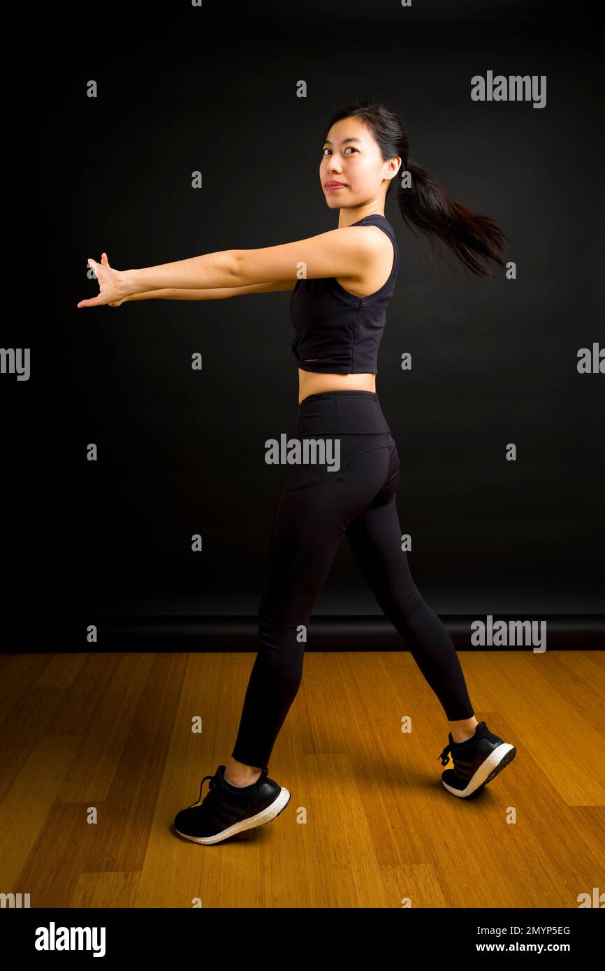 Adatta giovane donna asiatica che gira con le braccia tenute fuori e Ponytail Flying fuori Foto Stock