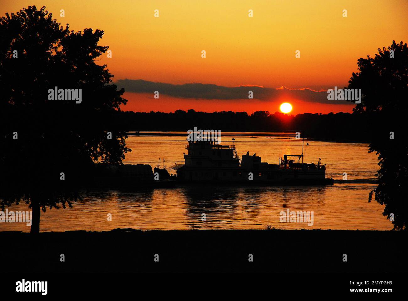 A River Barges naviga oltre il tramonto del sole lungo il fiume Mississippi vicino a Memphis, Tennessee Foto Stock