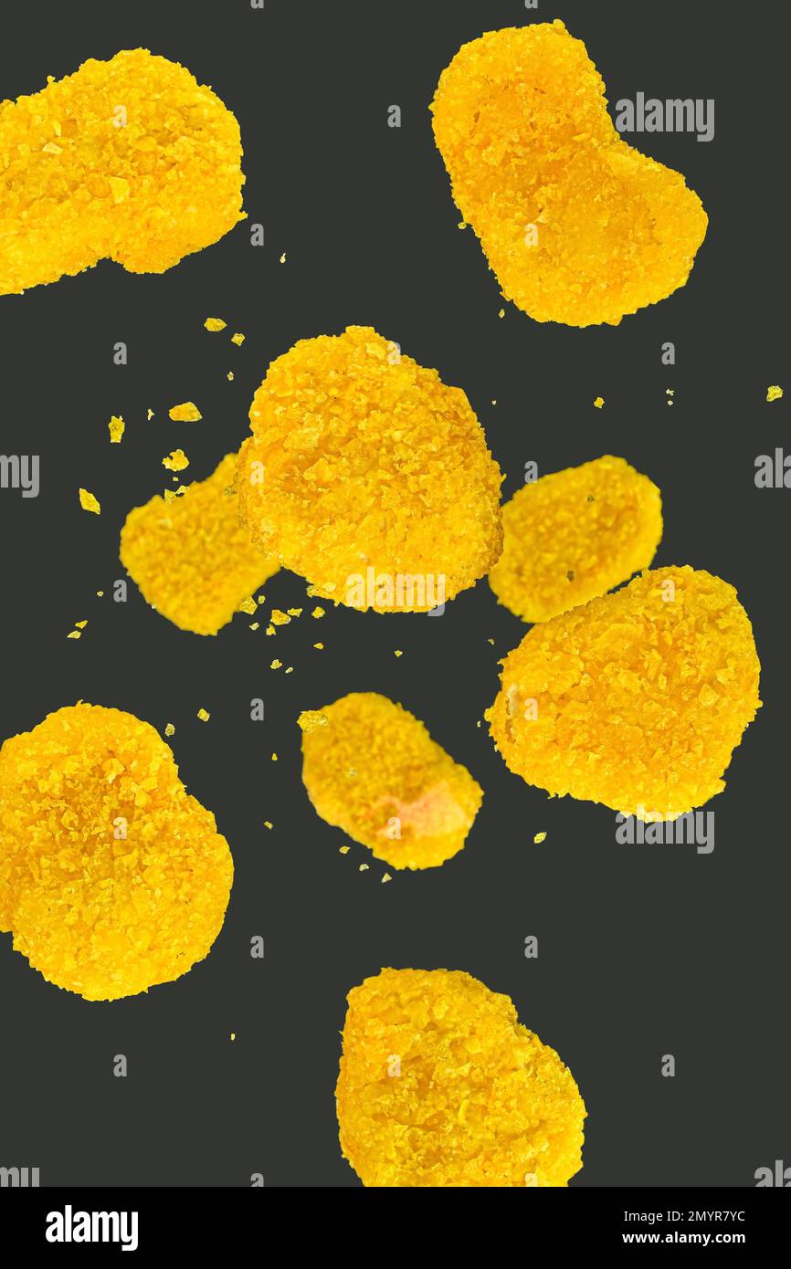 Pepite di pollo fresche che cadono su sfondo nero. Congela i pezzi di pollo volanti su sfondo nero. Alimenti volanti. Pepite di pollo su una bla Foto Stock
