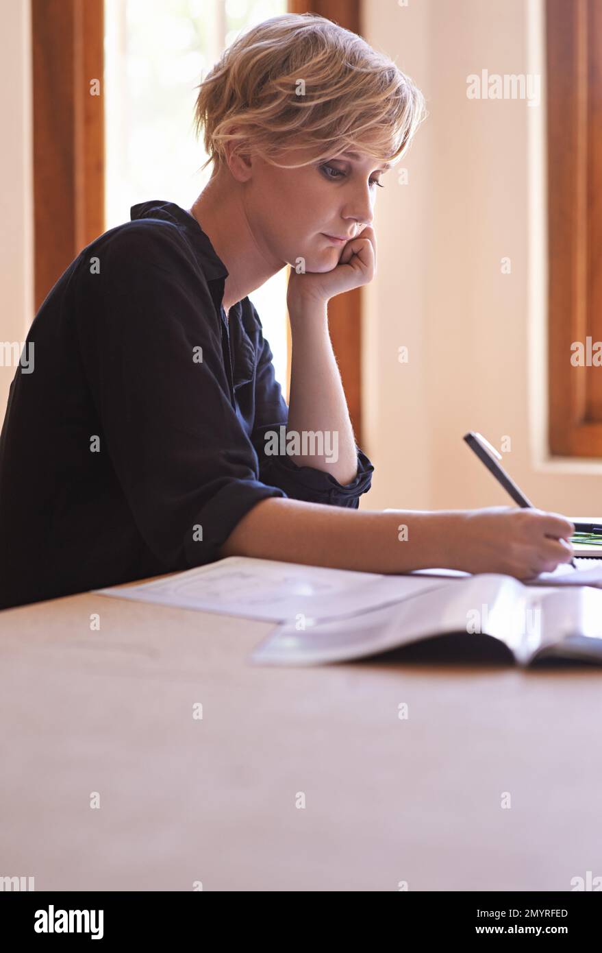 Una giornata lenta in ufficio... Un colpo corto di una bella giovane donna che lavora alla scrivania. Foto Stock