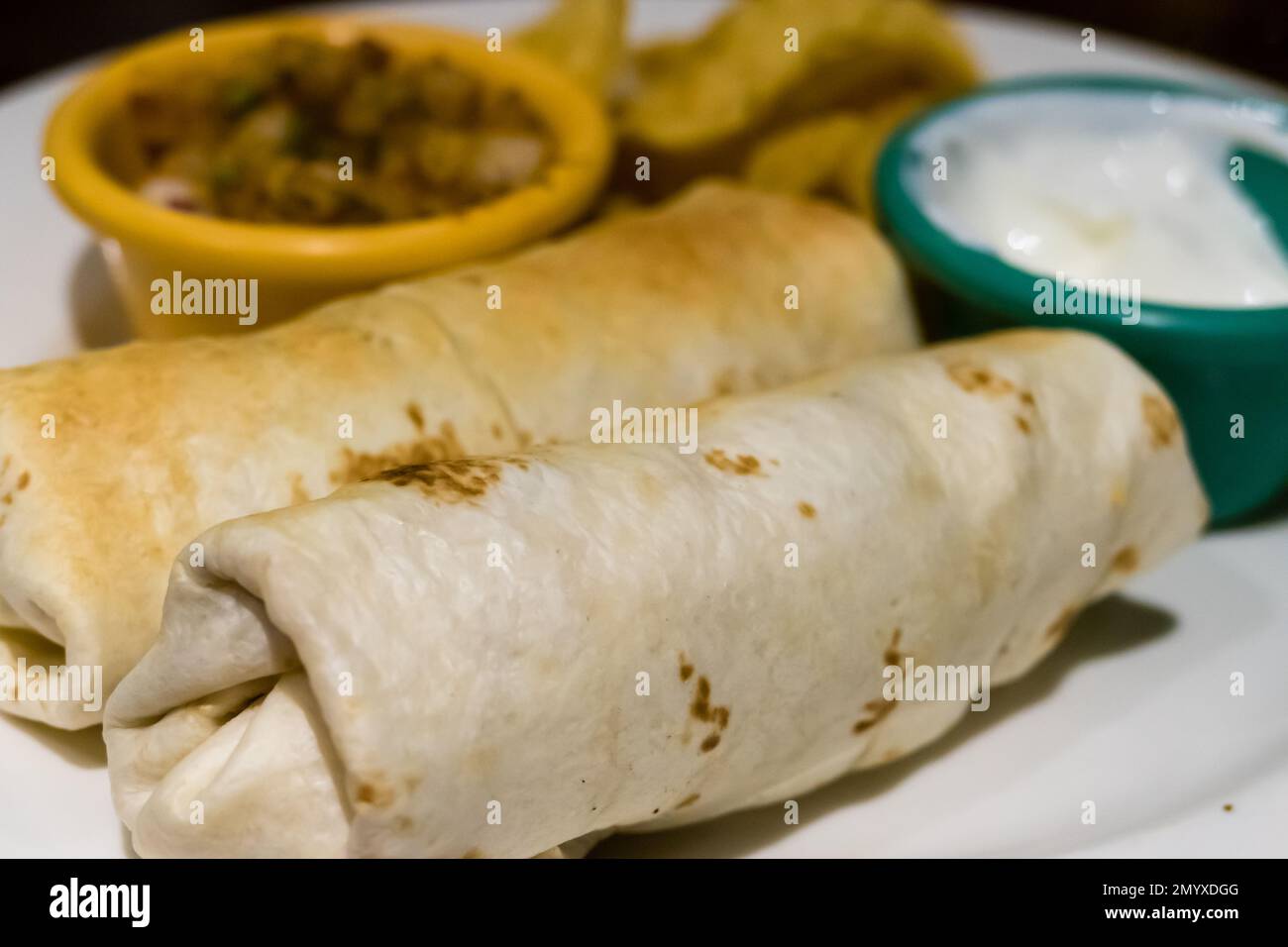 Burritos su piatto con salsa e creme Foto Stock
