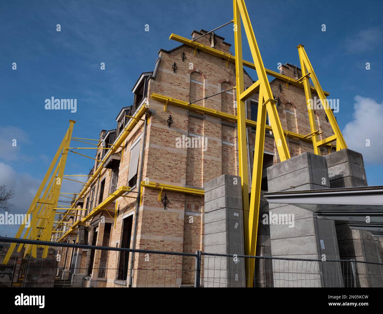 Sostenere i montanti e i contrappesi contro un grande complesso di alloggiamenti per garantire che i lavori di demolizione vengano eseguiti in modo sicuro Foto Stock