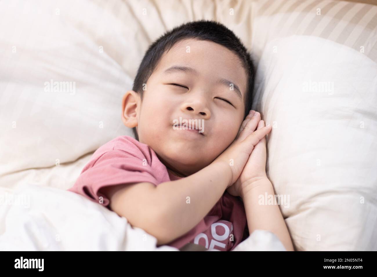 Un ragazzino in un letto comodo Foto Stock