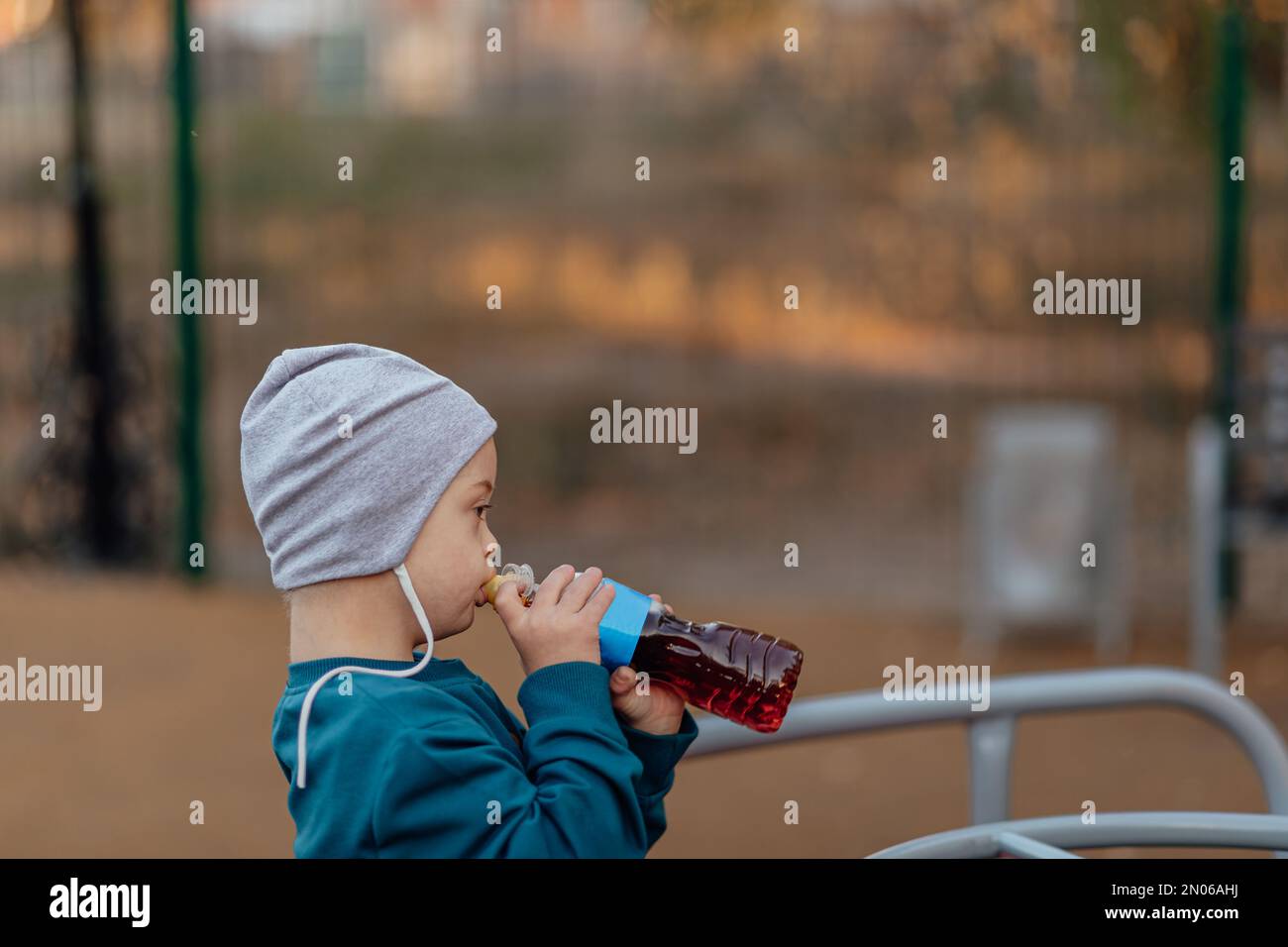 Ritratto di carino ragazzo con sindrome di Down godendo tè al parco, copia spazio Foto Stock