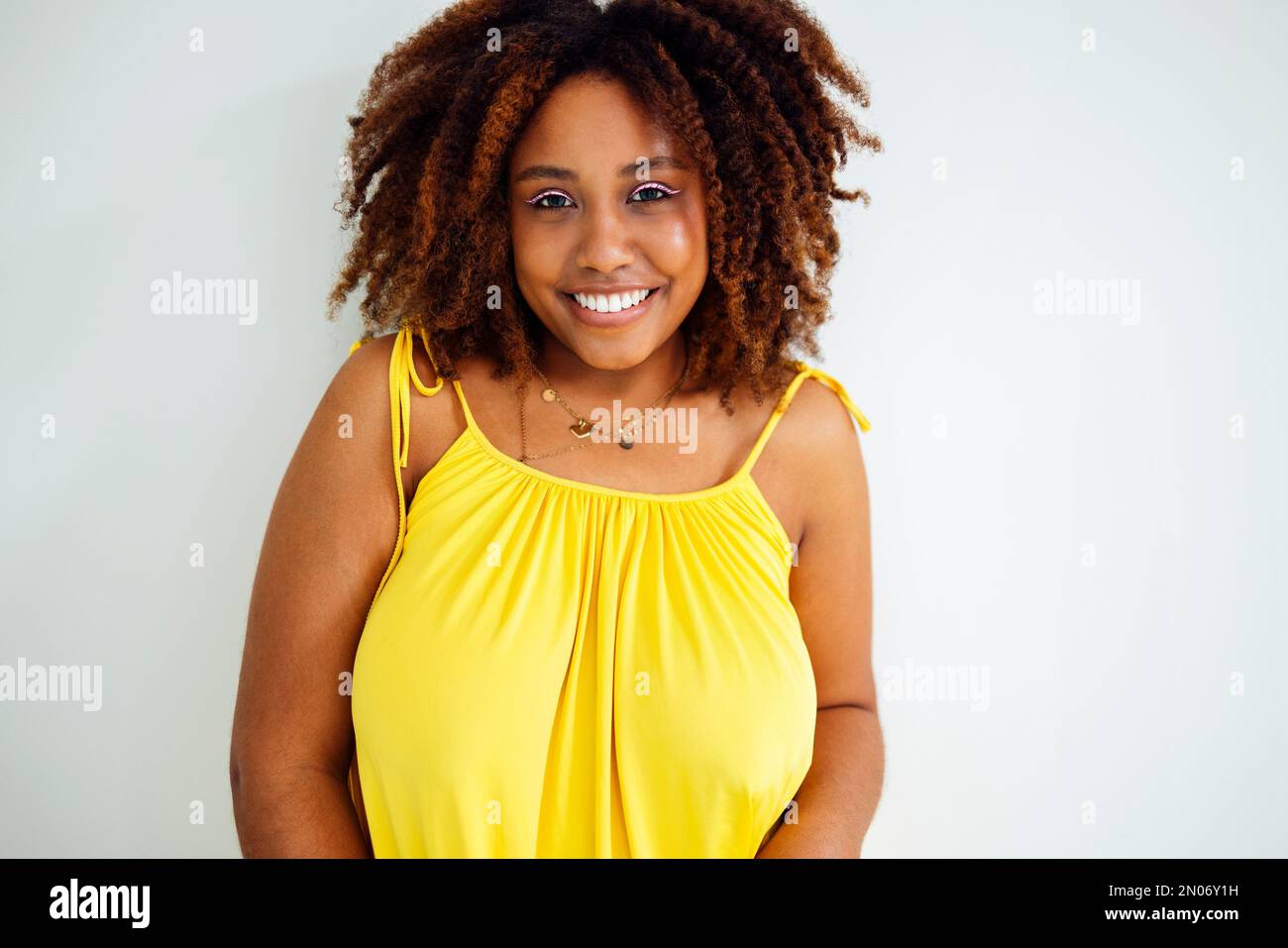 Bella curvy oversize giovane afto donna americana in un abito giallo a casa. Corpo positivo elegante donna sorridente hanno tempo di relax. Accettazione del corpo AN Foto Stock
