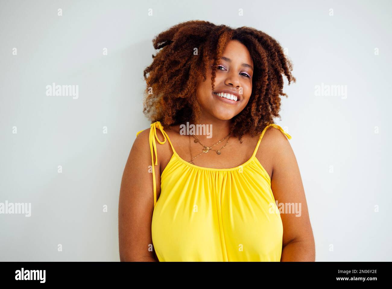 Bella curvy oversize giovane afto donna americana in un abito giallo a casa. Corpo positivo elegante donna sorridente hanno tempo di relax. Accettazione del corpo AN Foto Stock