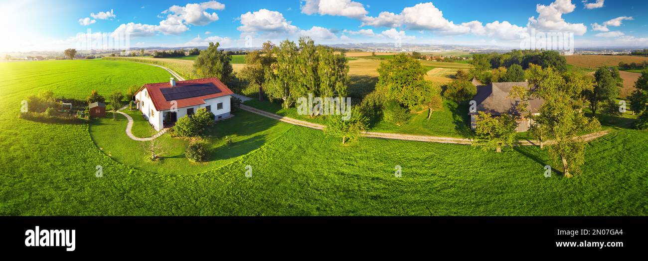 Casa in campagna idilliaca in Austria, Europa, con un pannello solare sul tetto circondato da un bellissimo prato e alberi Foto Stock
