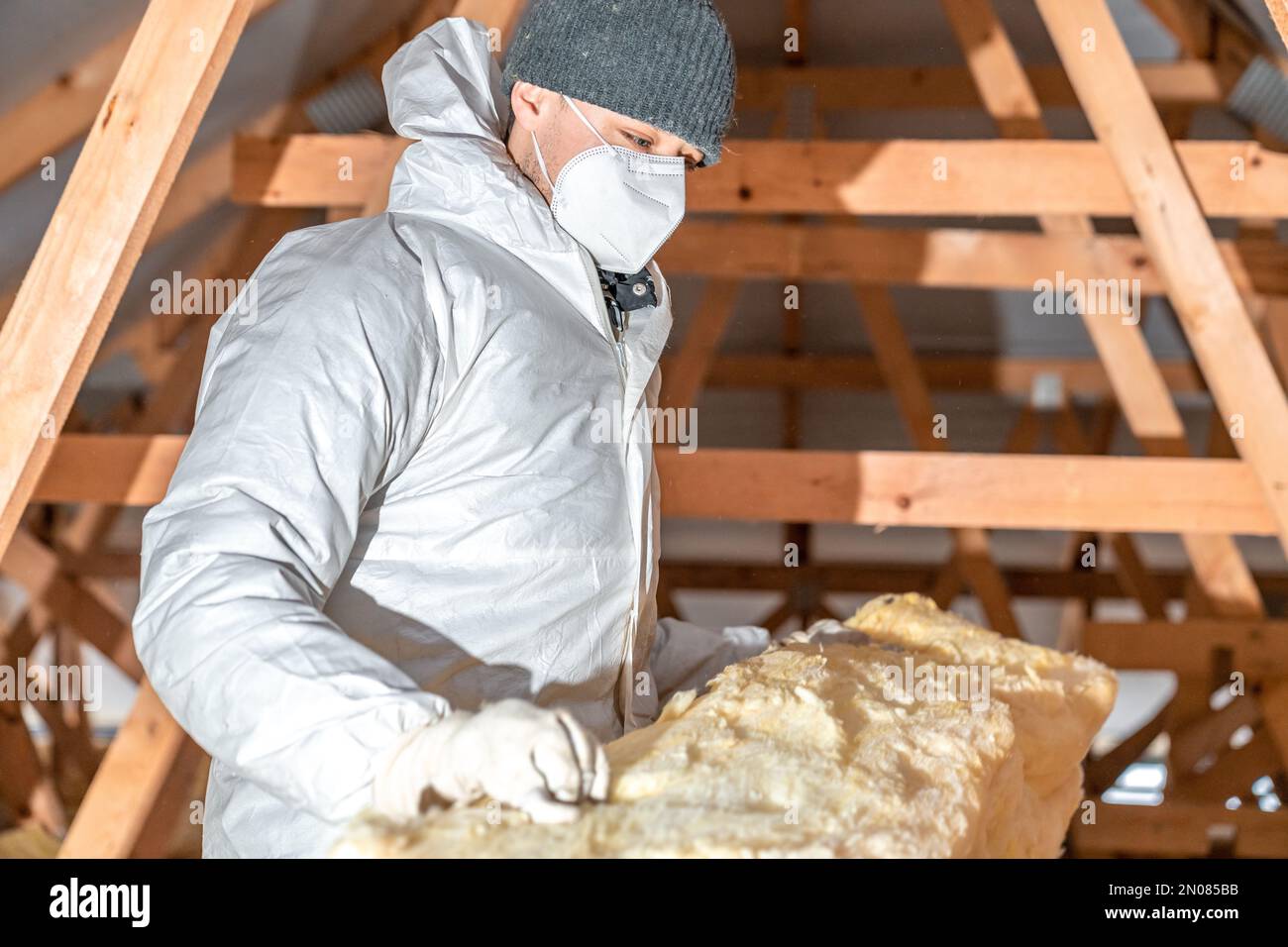 l'uomo isola il tetto e il soffitto della casa con lana di vetro Foto Stock