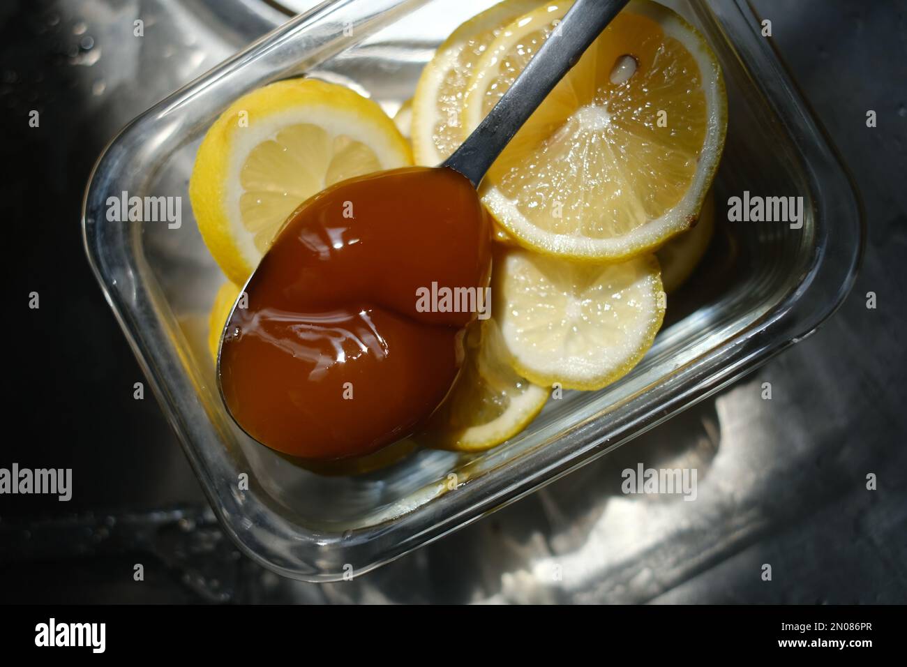 Ciotola di vetro piena di miele e fettine di limone Foto Stock