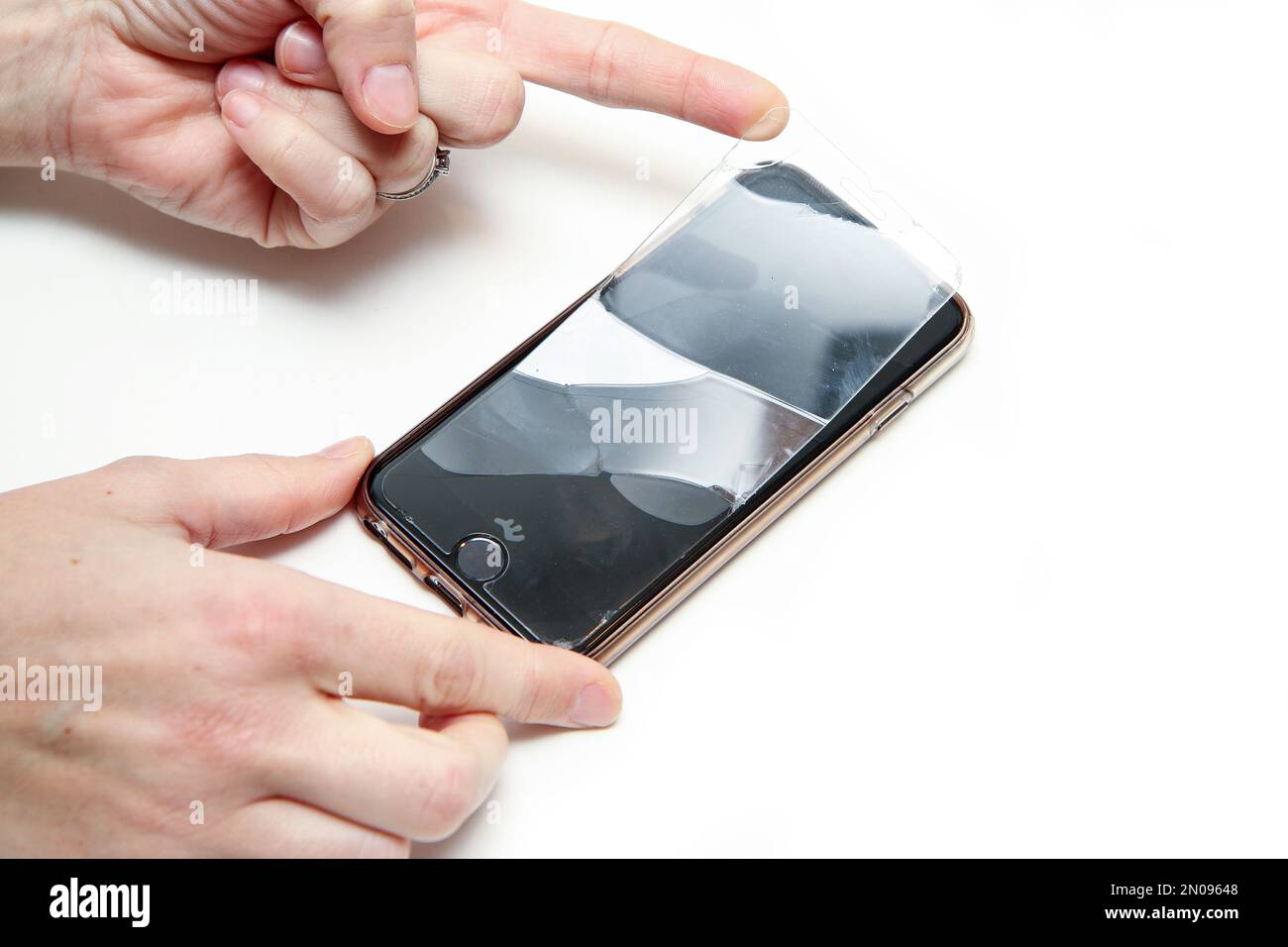 Il dettaglio delle mani che rimuovono il vetro di protezione rotto con incrinature dallo schermo a sfioramento dello smartphone. Foto Stock