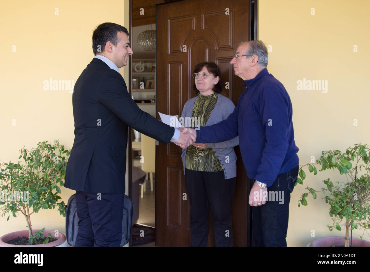 Immagine di un addetto alle vendite e di un venditore porta a porta che spiega i suoi prodotti per la vendita a una coppia più anziana. Venditrice e scammer molesti. Foto Stock