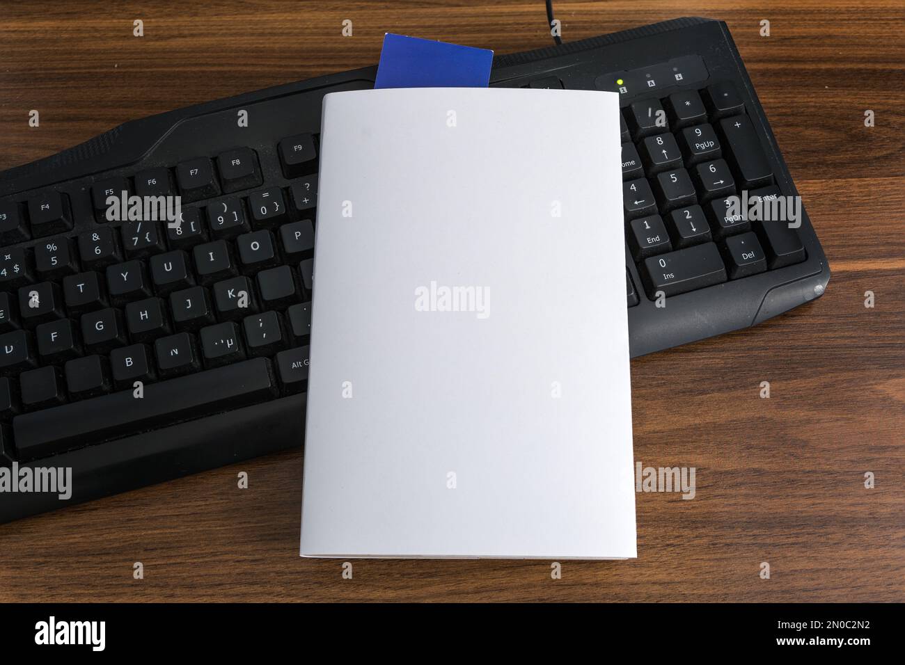 Modello di copertina bianco vuoto con segnalibro blu sulla parte superiore della tastiera nera . Tracciato di ritaglio. Foto Stock