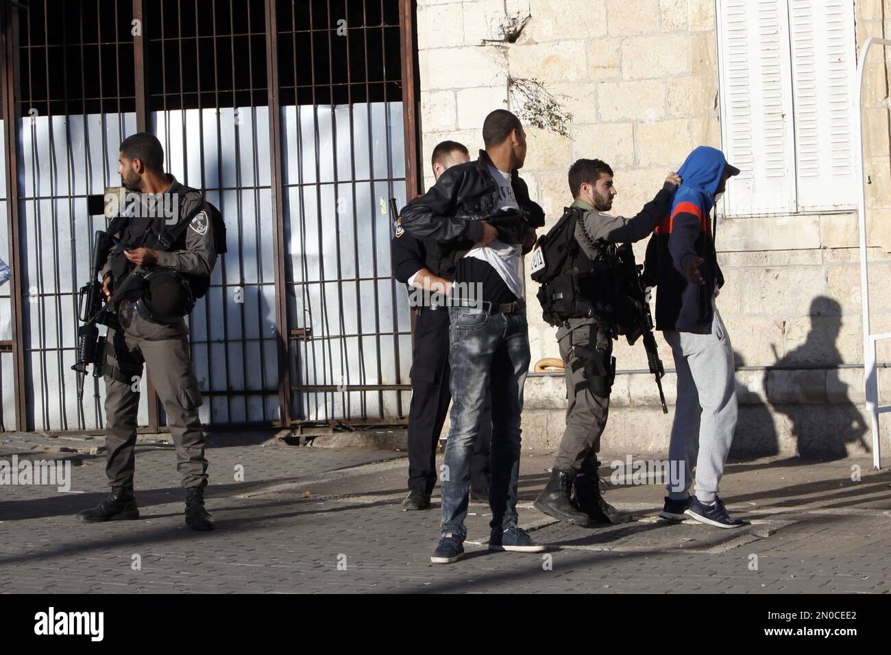 An Israeli police officer stands guard as others check a Palestinian near the scene of a shooting attack near the Damascus gate, Jerusalem's Old City, Wednesday, Feb. 3, 2016. Three Palestinians carrying automatic weapons, explosive devices and knives shot and stabbed two Israeli security officers in Jerusalem on Wednesday, wounding both before police shot and killed the attackers, police said. (AP Photo/Mahmoud Illean) Foto Stock