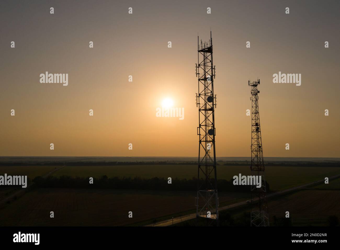 Il sole splende attraverso la silhouette delle torri di telecomunicazione Foto Stock